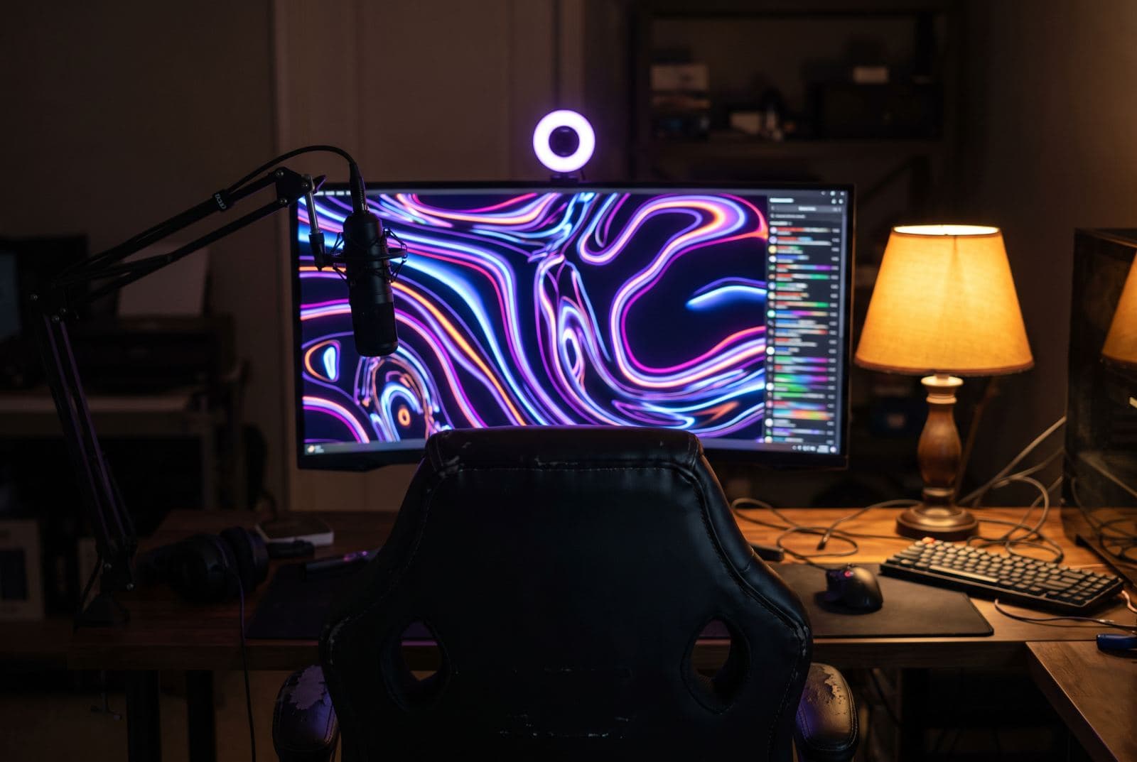 A streaming desk at night with a glowing monitor and a microphone